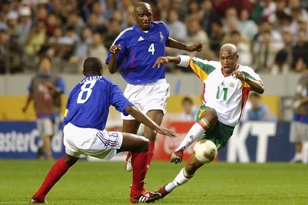 França 0 x 1 Senegal (2002) - Na abertura da Copa de 2002, a atual campeã mundial França foi surpreendida por Senegal, que fazia sua estreia em Mundiais. Mesmo sem Zidane, os franceses eram favoritos absolutos, mas acabaram eliminados ainda na fase de grupos, enquanto os africanos chegaram até as quartas de final. por Divulgação/FIFA