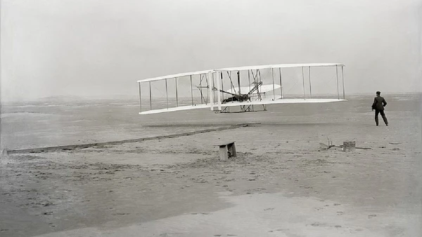 Em 1903, o Wright Flyer consolidou o voo motorizado, controlado e sustentado, marco que transformou experimentos em aviação moderna por John T. Daniels / Wikimedia Commons