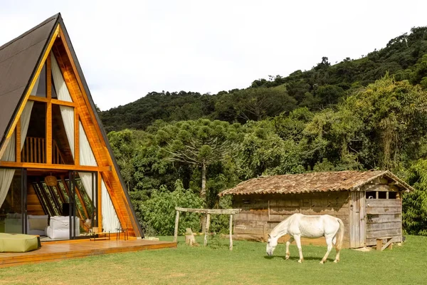 Cabana de Yanna Lavigne e Bruno Gissoni aposta em arquitetura de vidro, sauna a lenha e vista para a Serra da Mantiqueira por Manuel Sá