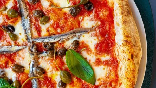 Pizza Napoletana, da Itália, é preparada com massa de borda alta, molho de tomate, queijo e manjericão por C1 Superstar / Pexels