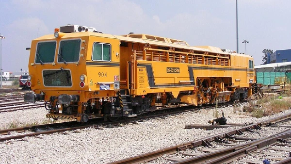 A socadora compacta as pedras sob os trilhos, conhecidas como lastro. Esse material ajuda a distribuir o peso dos trens, estabilizar os dormentes e manter o alinhamento da via